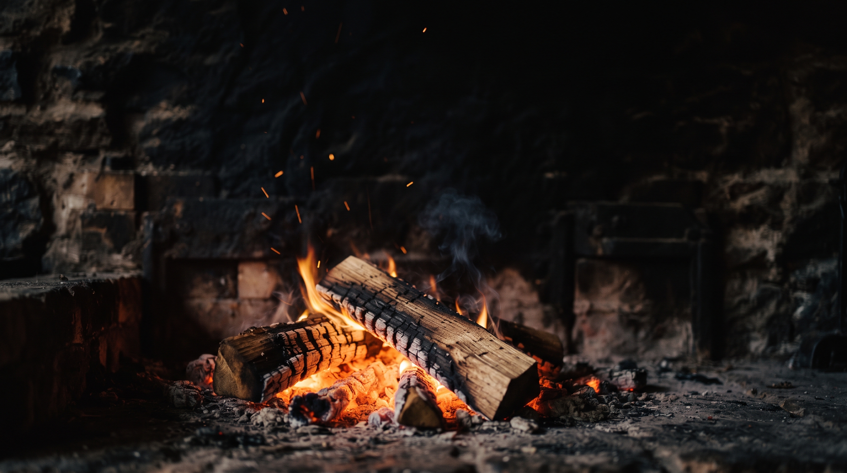 Glowing embers and burning oak in an open hearth, smoke rising into darkness